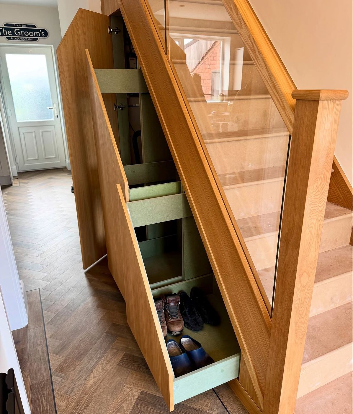 Bespoke pull-out shoe storage built into the triangular space beneath an oak staircase