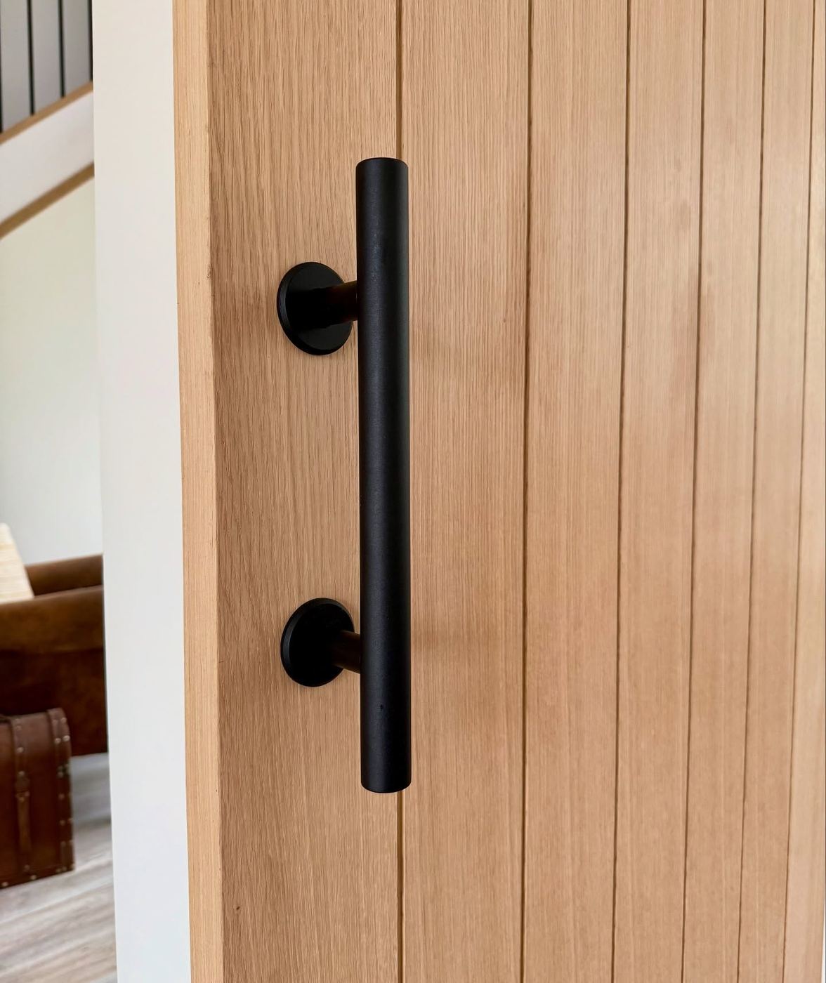 Matt black bar handle mounted on a vertical tongue and groove oak door