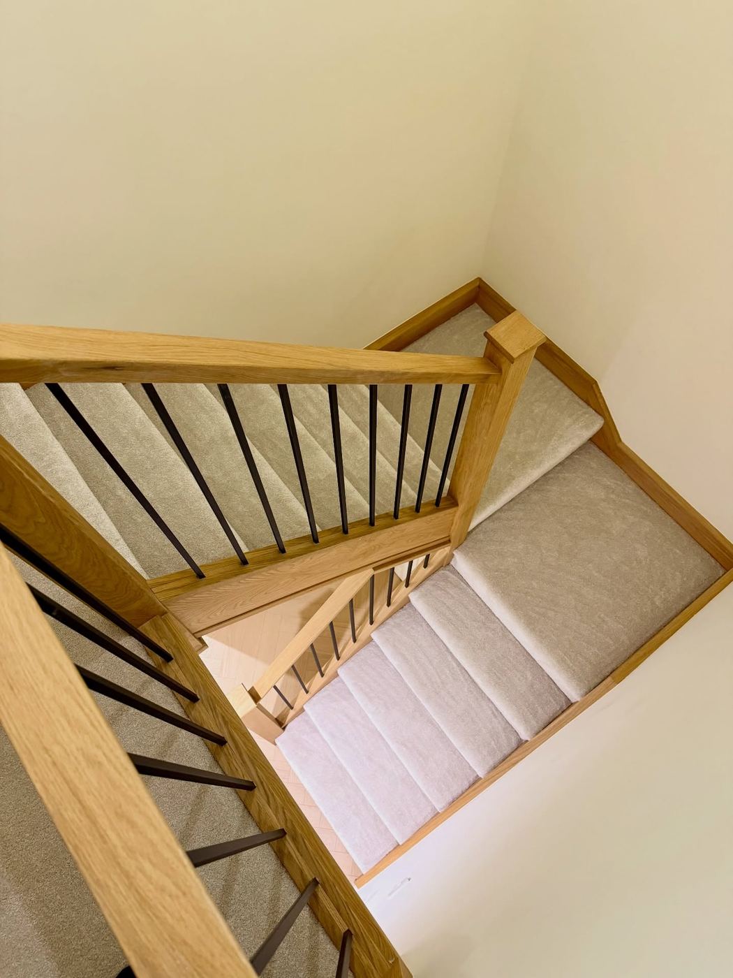 Oak staircase and landing balustrade with slim black spindles, photographed from above